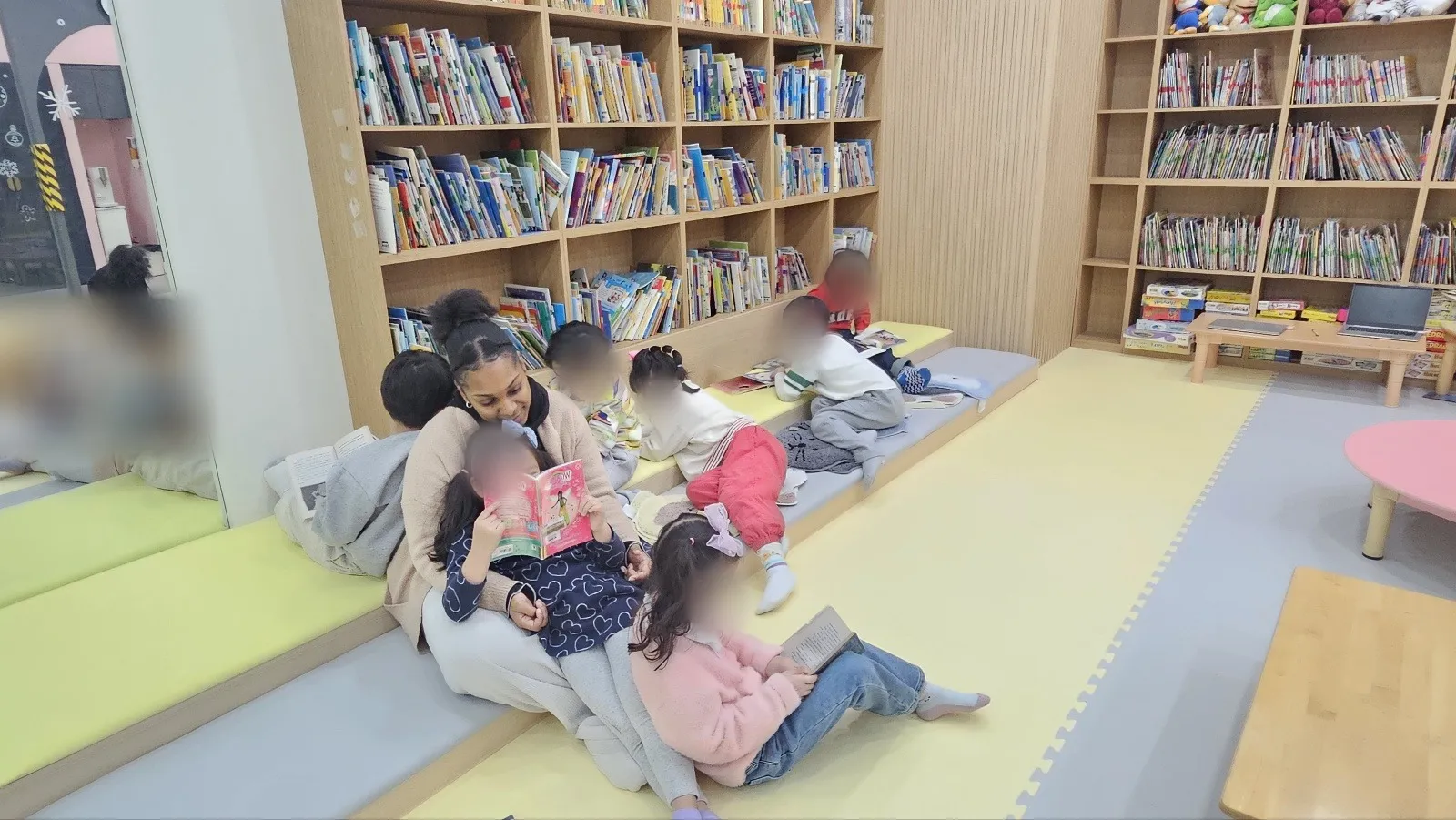 라이즈 동탄1 원어민 선생님이 도서관에서 아이들과 함께 책을 읽는 모습